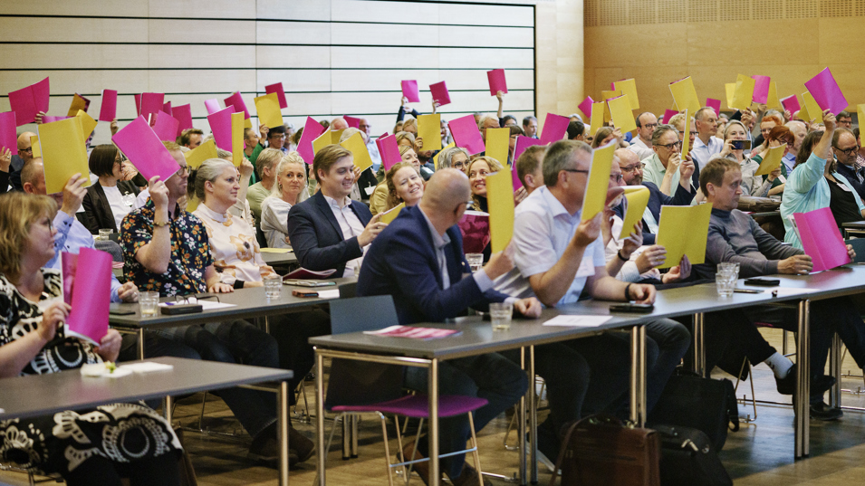 Publikum ved Arbejdsmiljøprisen holder stemmersedler op